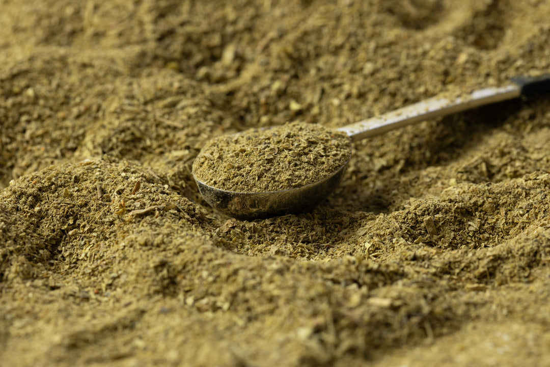 Organic fermented superfood supplement in a metallic scoop, golden-brown, with finely textured, herbal-like appearance.