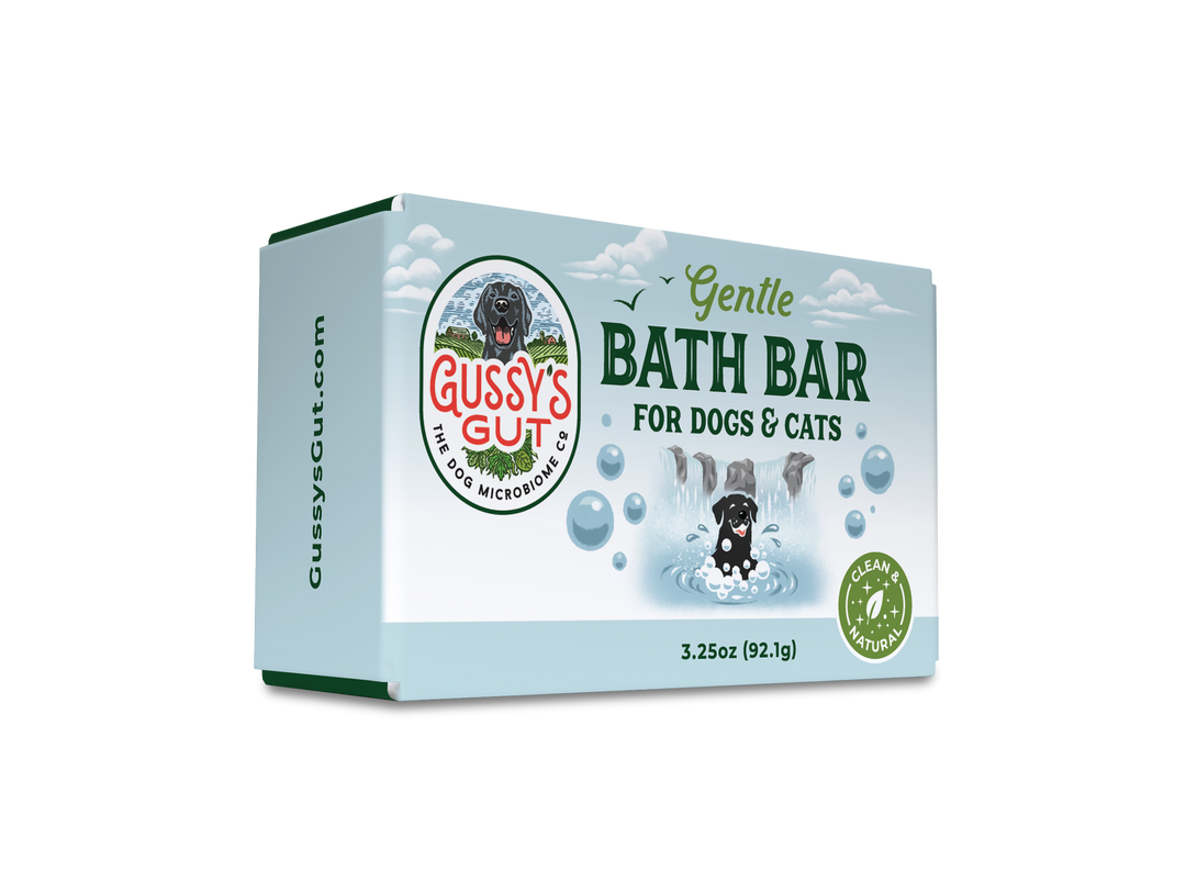 Eco-friendly dog and cat bath bar in light blue packaging with a playful black dog image, green accents, and "Gussy’s Gut"...
