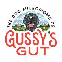 Logo featuring a black dog with open mouth, surrounded by farm fields and buildings, with "Gussy’s Gut" in bold red letters.