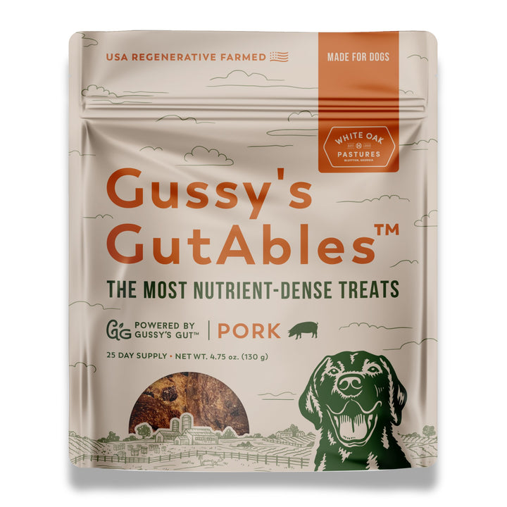 Gussy's GutAbles™ Treats package featuring White Oak Pastures pork, with a smiling dog illustration and farm scenery.